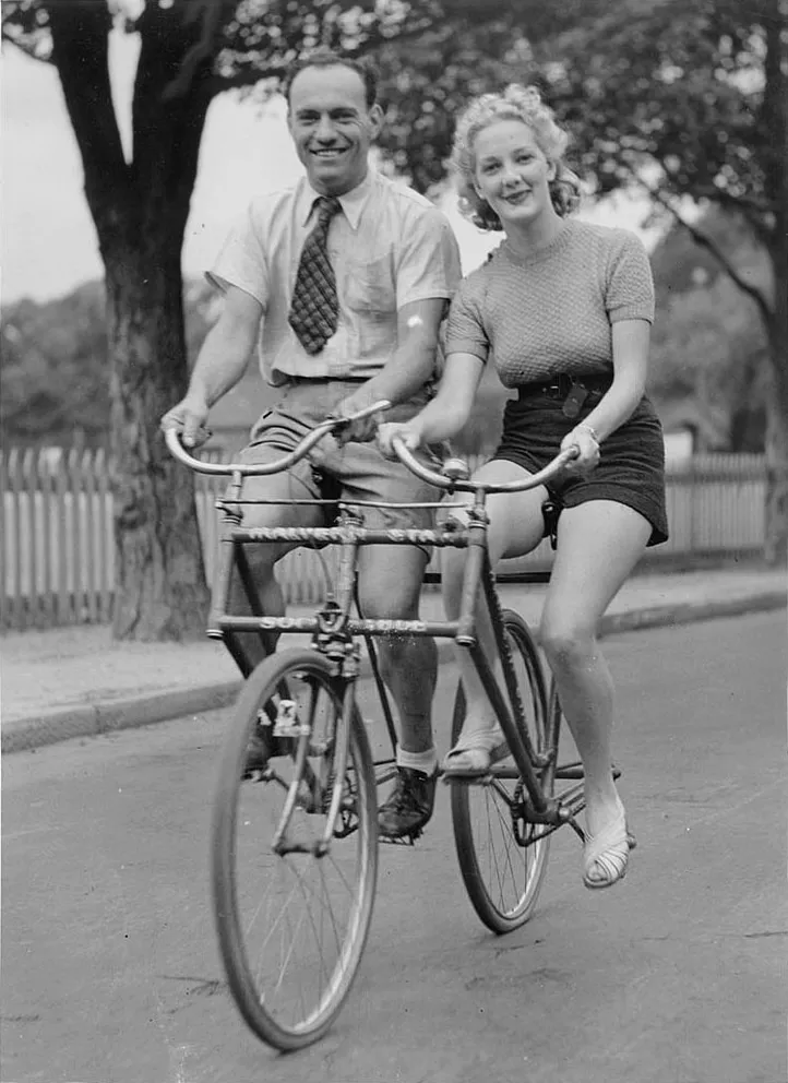 Man_and_woman_on_a_Malvern_Star_abreast_tandem_bicycle,_c._1930s,_by_Sam_Hood, State Library of Australia, Public Domain.jpg